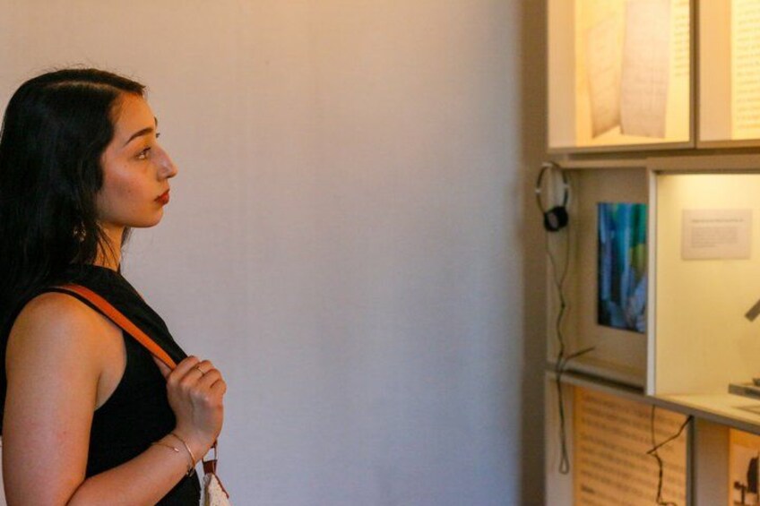 A person standing in front of a display case with papers and a blue object. 3