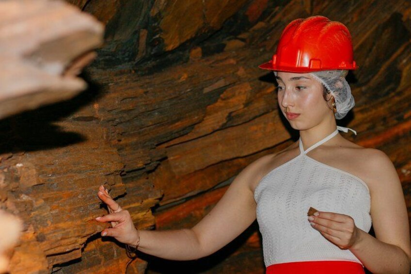 A person in a red hard hat and white tank top, holding a small object. 2