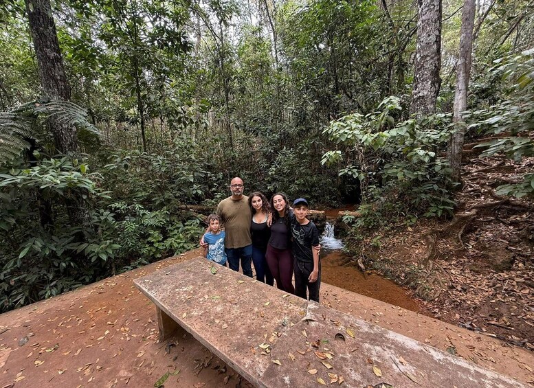 A family standing on a wooden platform in a forest with a small stream. 5