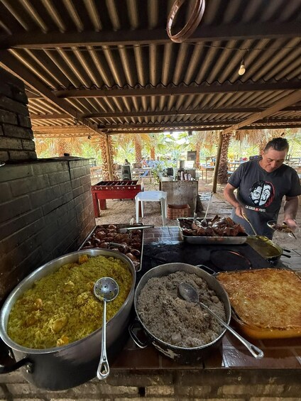 An outdoor food stall with various dishes, a grill, and a person serving food. 2
