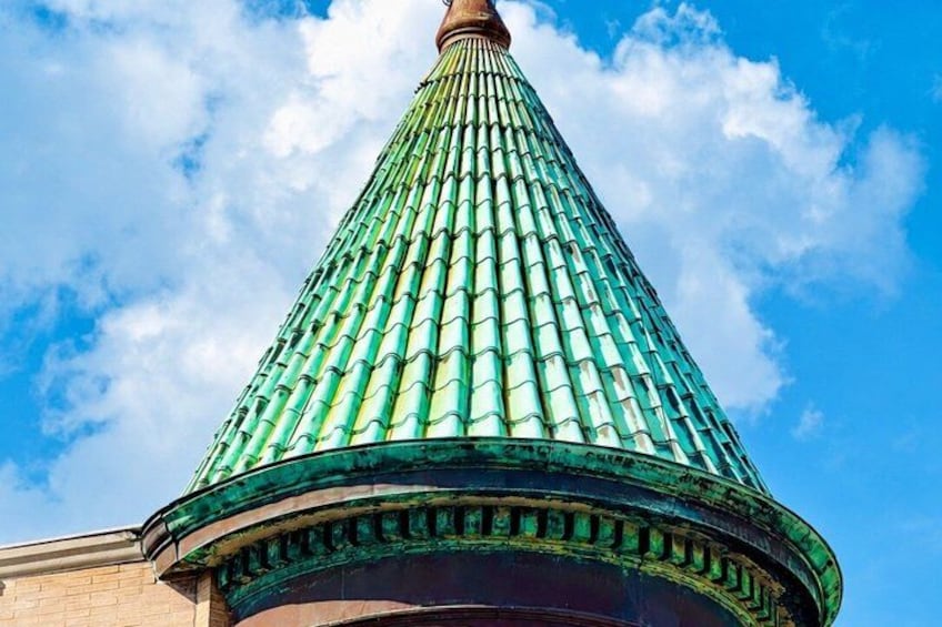 A green conical roof with a brick base against a blue sky. 3