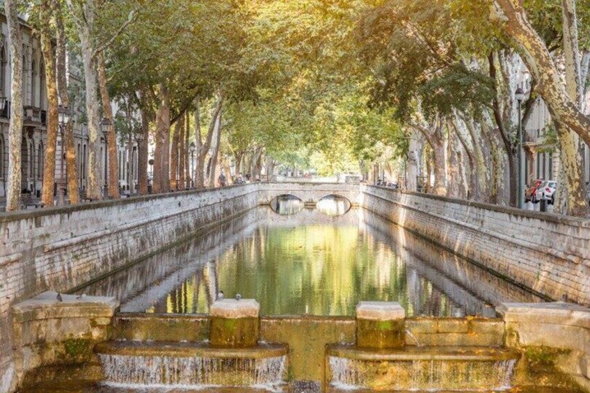 A canal lined with trees and a stone bridge in the distance. 4