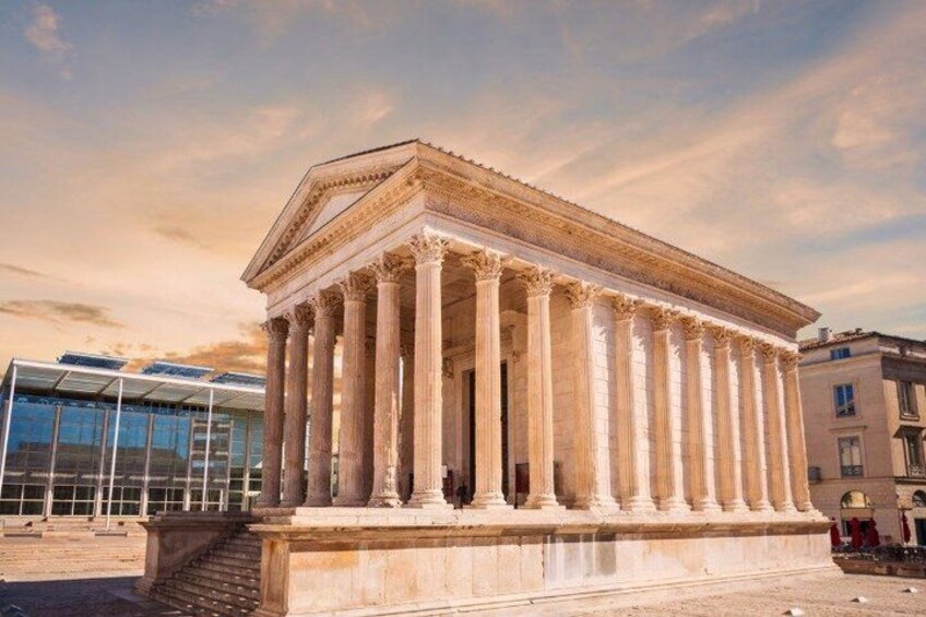 A classical building with columns, a clear sky, and modern buildings in the background. 2