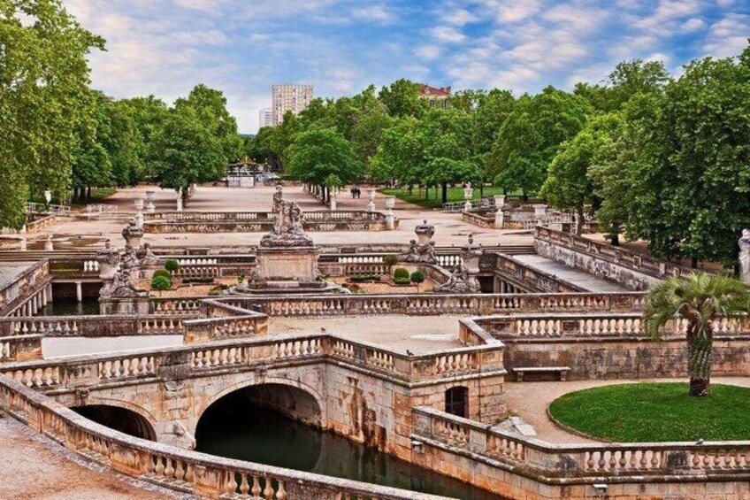 A historic garden with ornate stone bridges, a central fountain, and lush greenery. 5