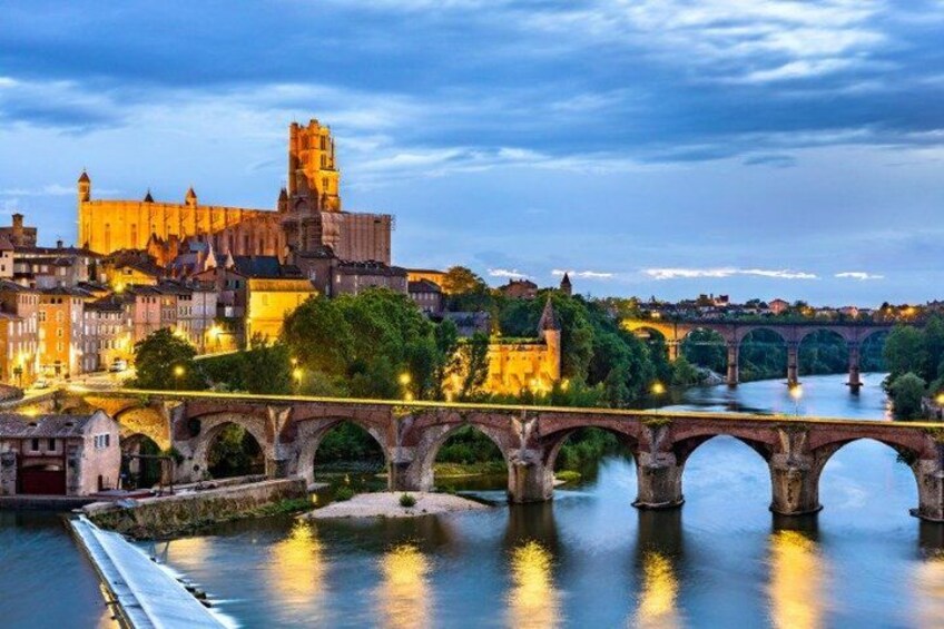 A historic bridge over a river, a castle, and a cityscape at dusk. 4