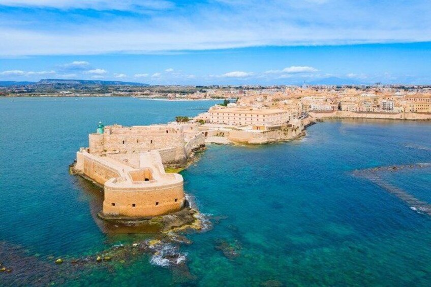 A coastal fortification with a clear view of the surrounding water and distant cityscape. 2