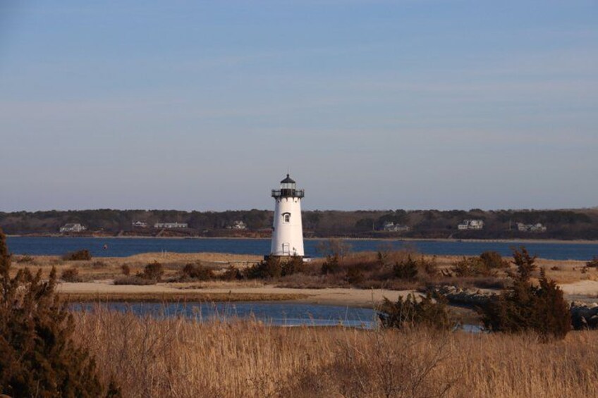 A white lighthouse by a body of water with a clear sky. 4