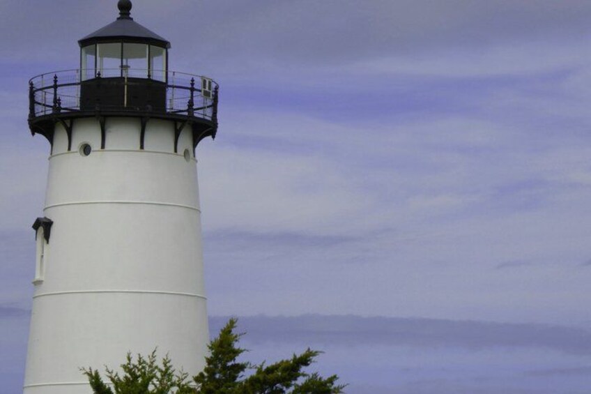 A white lighthouse with a black top and a glass lantern room. 5