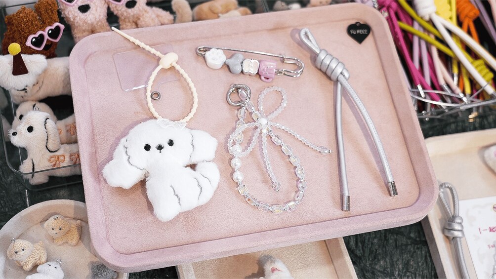 A pink tray with various keychains and a plush toy. 2