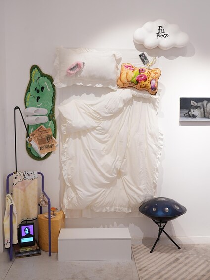 A room with a bed, a wall decoration, a framed picture, a small table, and a chair. 3