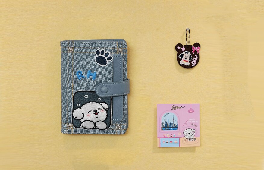 A denim phone case with a bear design, a keychain with a bear, and a card with a cityscape. 5