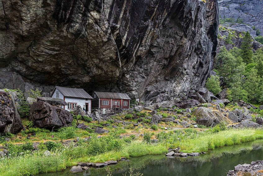 Un chalet rustique niché dans un défilé rocheux, avec une rivière en premier plan. 1