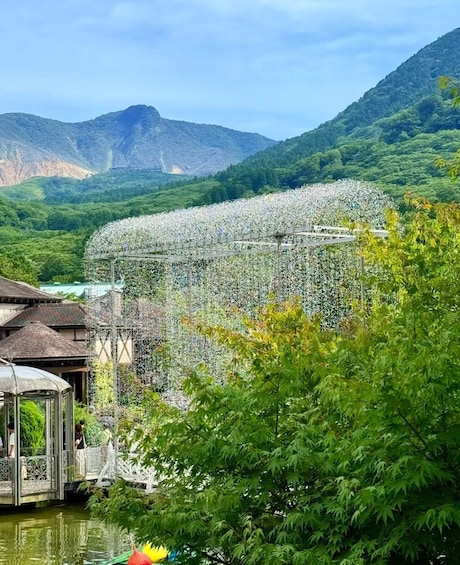 A garden with a large white structure, surrounded by lush greenery and mountains in the background. 3