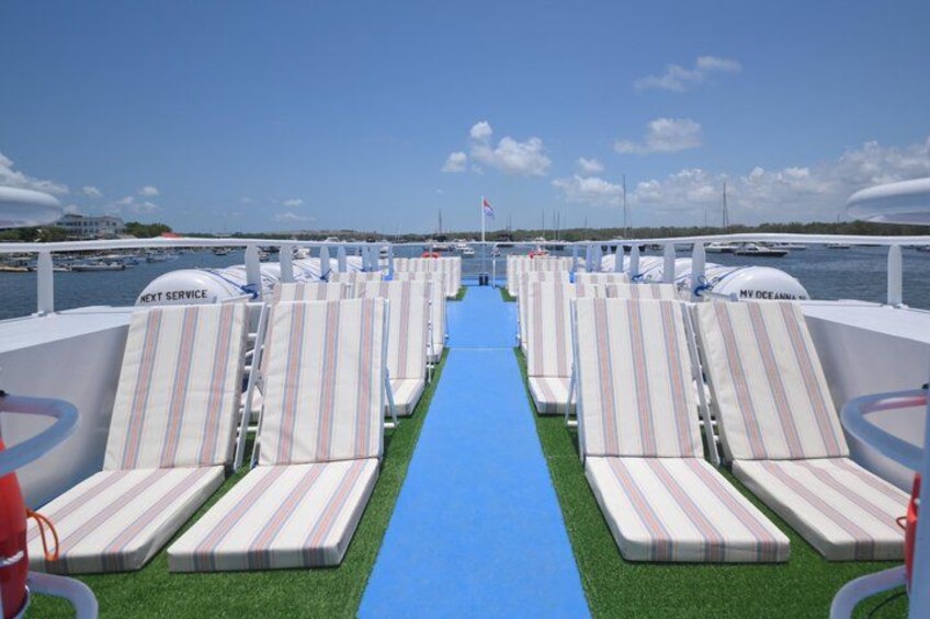 A boat deck with rows of striped lounge chairs and a blue carpet leading to the water. 4