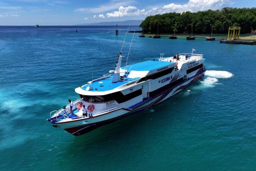 A large white and blue boat named 'Oceanis' cruising on turquoise waters with a clear sky and distant land. 1