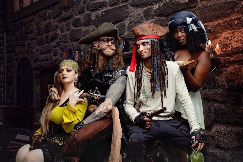 A group of people in pirate-themed costumes sitting in front of a stone wall. 5