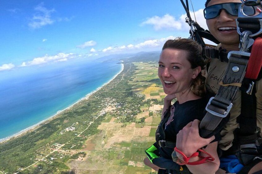 A person in a harness and safety gear, with a scenic view of a coastline and ocean. 5
