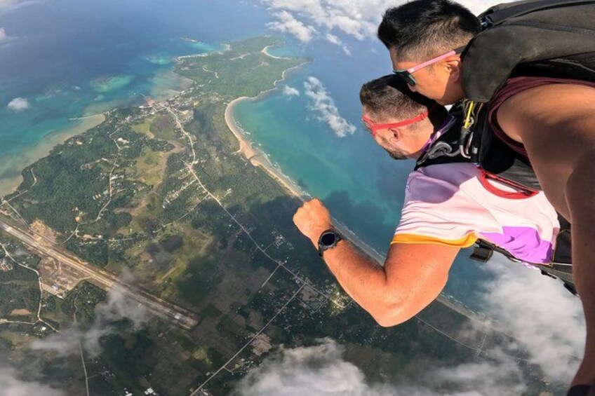 Two people skydiving with a landscape view below. 3