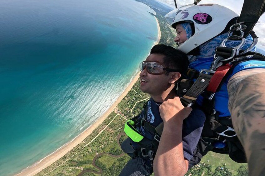 A person skydiving with a parachute over a coastal landscape. 2