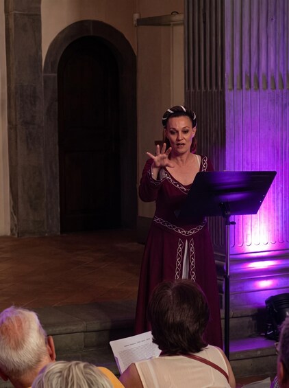 Une personne fait une présentation dans une salle où la scène est illuminée de lumière violette et où l’entrée est surmontée d’un arc. 2