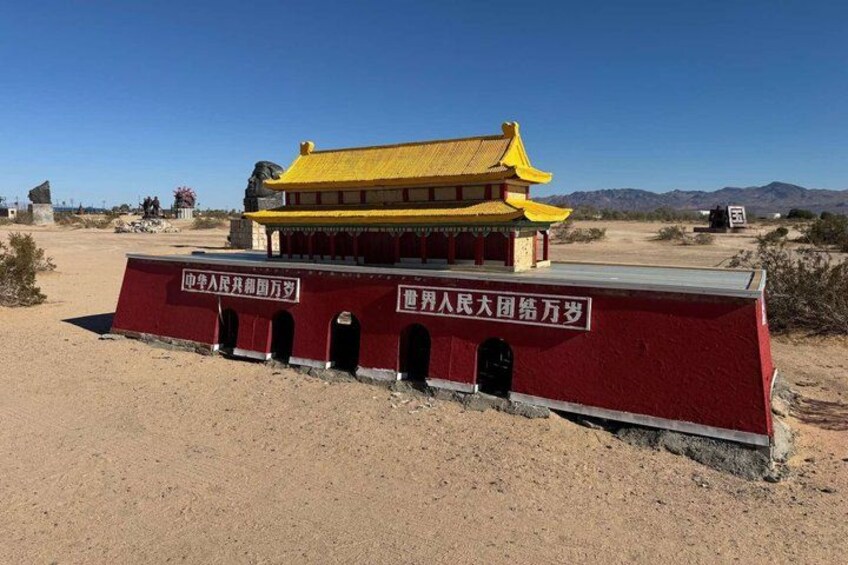 A traditional Chinese building with a yellow roof and red walls, surrounded by a desert landscape with mountains in the background. 5