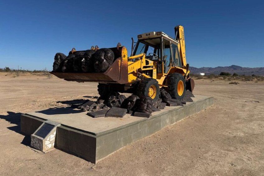 A yellow front loader with a bucket full of rocks, parked on a concrete platform in a desert landscape. 4