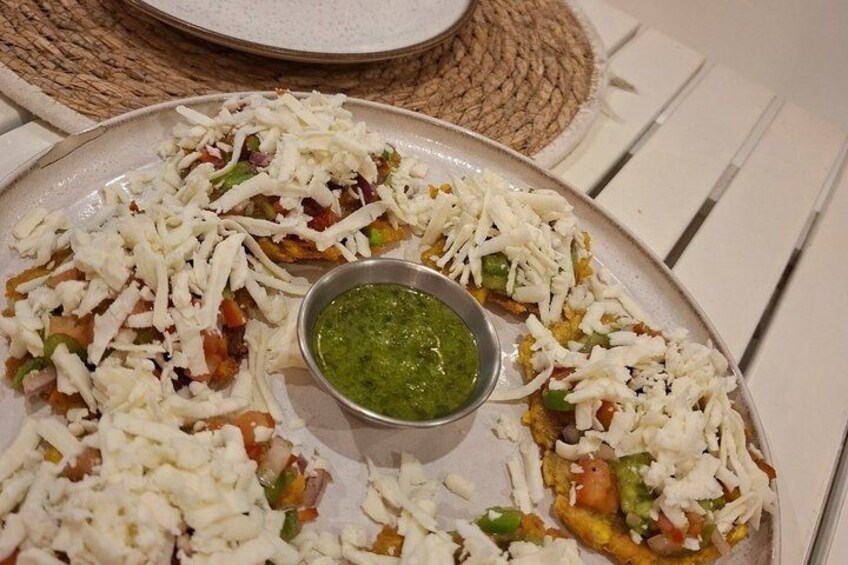 A plate of food with shredded cheese, vegetables, and a green sauce. 2