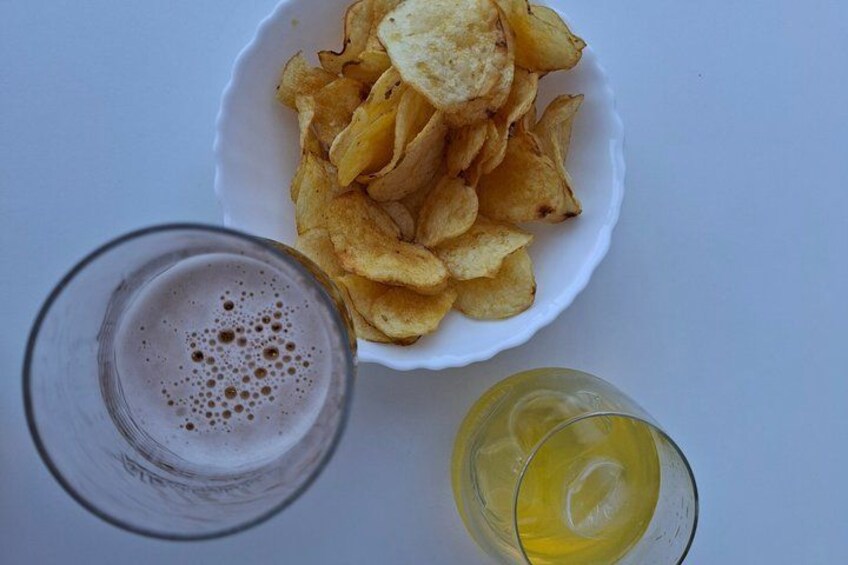 A bowl of chips, a glass of beer, and a glass of juice. 1