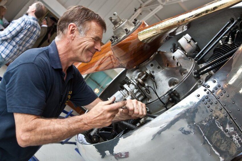 A person working on a metallic aircraft engine. 3