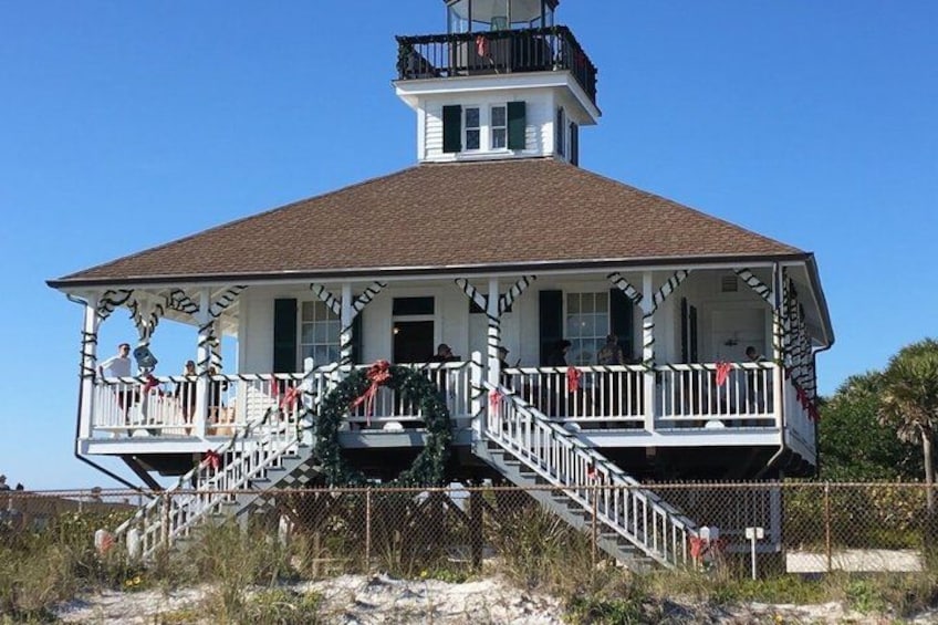 A white building with a brown roof, a balcony, and a staircase leading to the entrance. 5