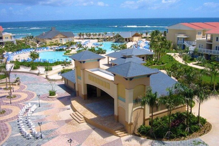 A resort with a swimming pool, palm trees, and a view of the ocean. 4