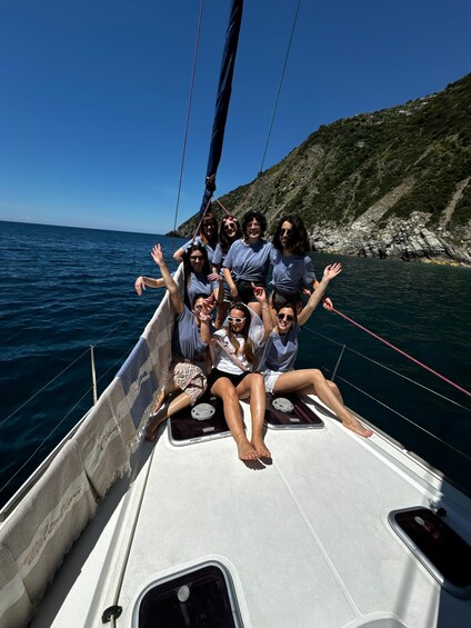 Eine Gruppe von Menschen auf einem Segelboot vor einer felsigen Küstenlinie. 2