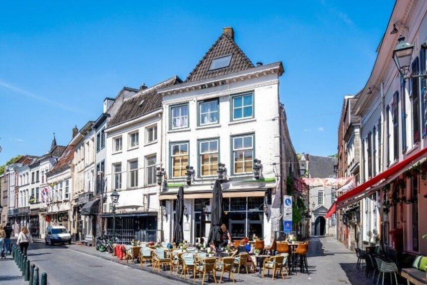 A street with a café, white buildings, and a clear blue sky. 4