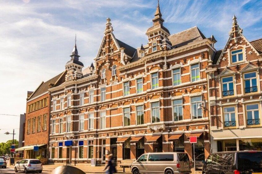 A historic building with ornate architecture, a street with cars, and a pedestrian. 5