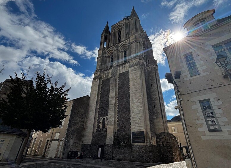 Una iglesia histórica con un alto campanario, rodeada de edificios y un cielo despejado. 3