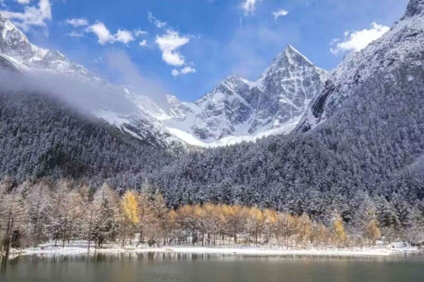 A snow-covered mountain range, a lake, and a forest with autumn-colored trees. 2