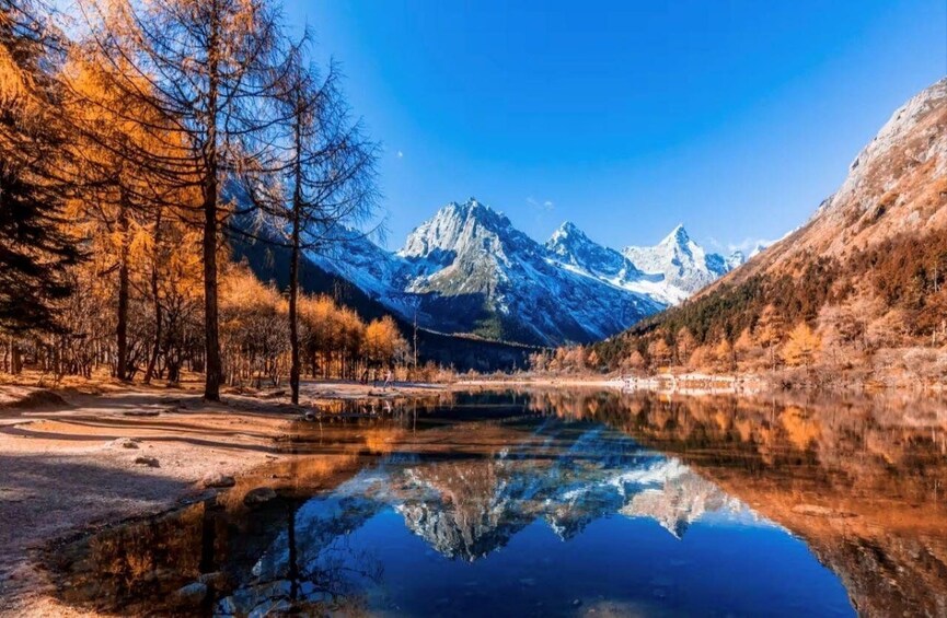 A mountain landscape with a lake reflecting trees and mountains. 1