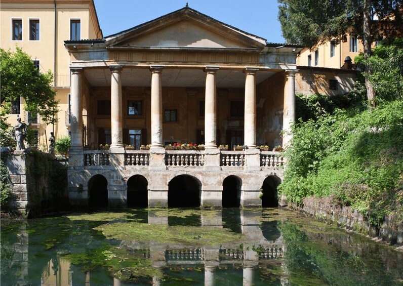 A classical building with columns, a portico, and a reflection in the water. 4