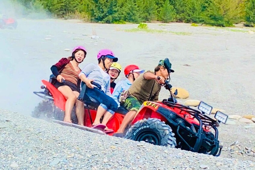 A group of people on a red ATV on a gravel path with trees in the background. 5