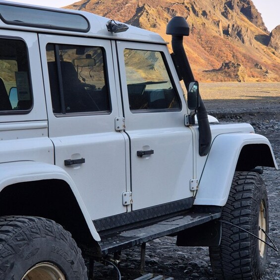 A white off-road vehicle with large tires and a winch on the front. 2