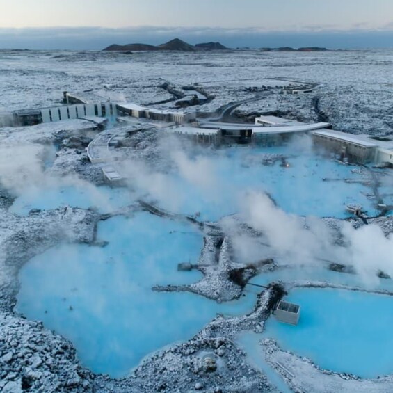 A geothermal spa with blue pools and steam rising from the ground. 1