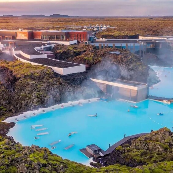 A geothermal spa with pools, a modern building, and a volcanic landscape. 3