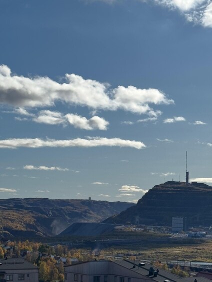 A landscape with a hill, buildings, and a clear sky with clouds. 5