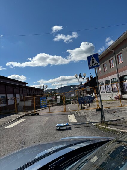 A pedestrian crossing sign, a yellow barricade, and a parking area with a blue sign. 2