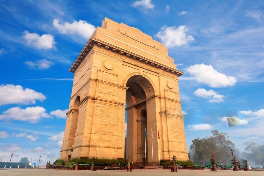 India Gate, et stort stensøjle med en buet indgang, mod en klar blå himmel med spredte skyer. 5