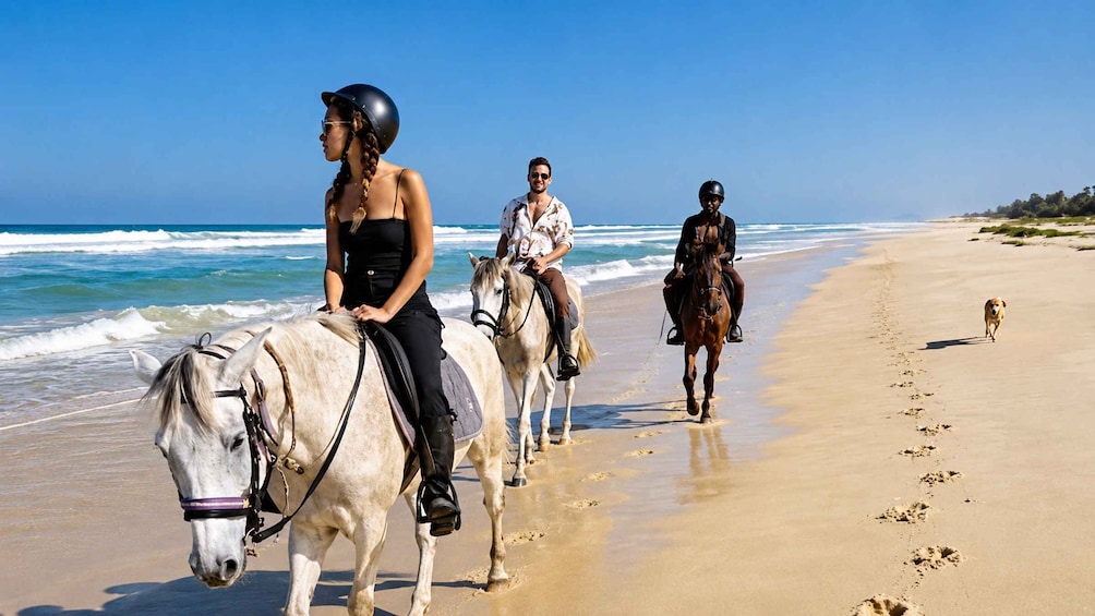 Three people horseback riding along a beach with ocean waves in the background. 4