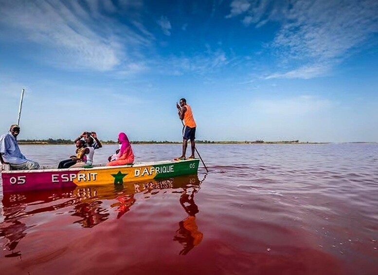 A boat with people on it, a person standing on the edge of the boat, and a clear sky. 2