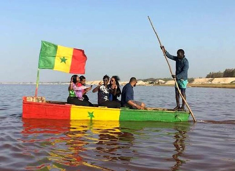 A boat with a flag, people on board, and a person standing on the shore. 5