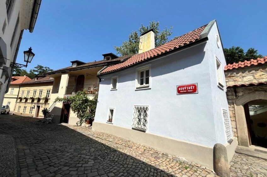 A cobblestone street with a white building with a red-tiled roof and a sign that reads 'NOWY SUJET.' 3