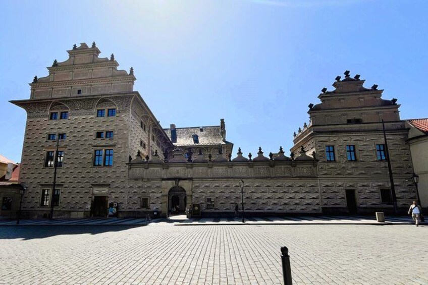 A historic building with ornate architecture, a paved courtyard, and a clear blue sky. 5